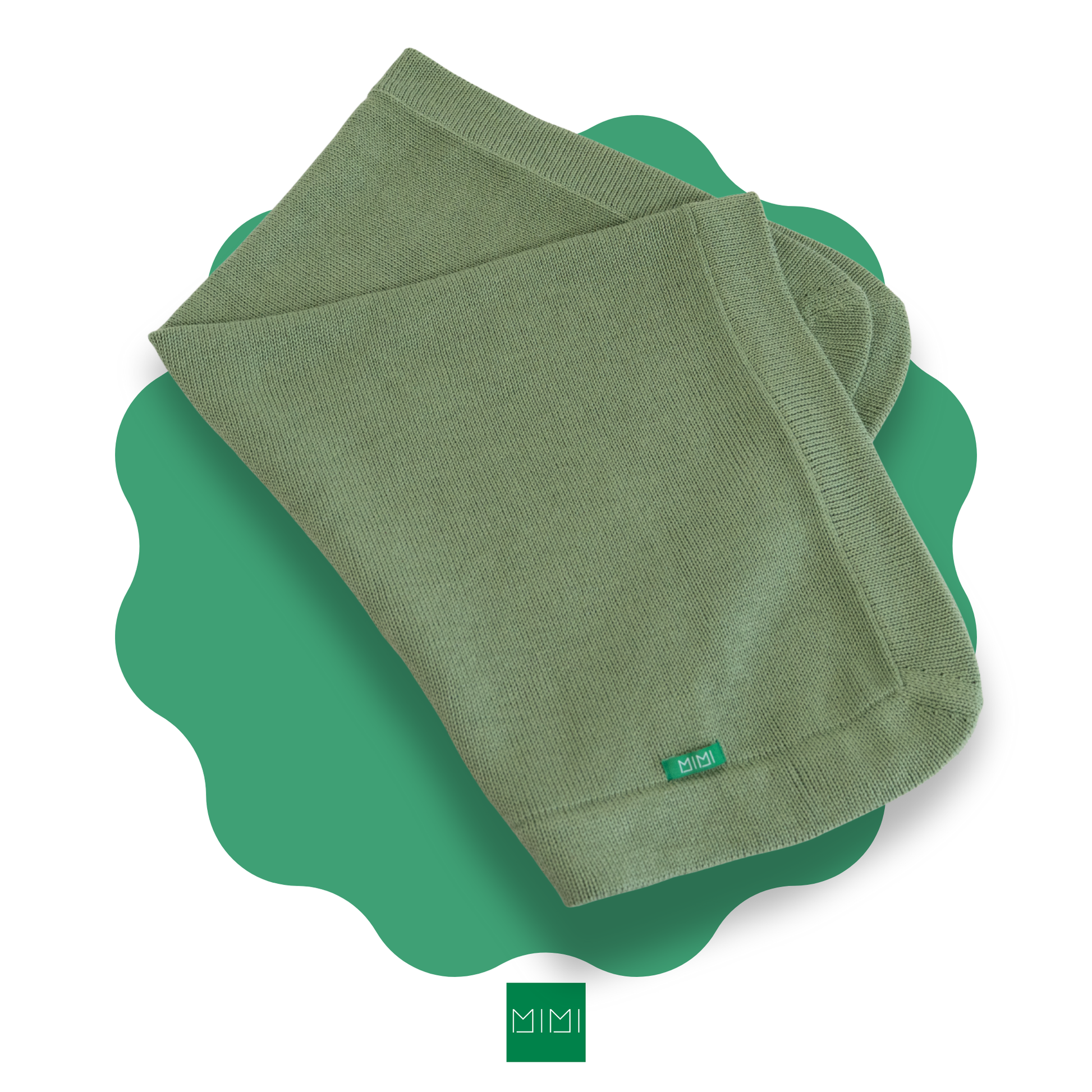Folded sage green knit newborn blanket on a green scalloped mat with 'MIMI' brand logo